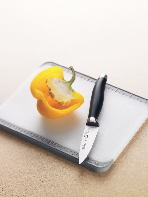 A pepper and paring knife on a cutting board. 